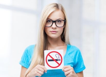 dívka držící zákaz kouření u vchodu